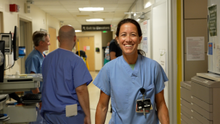 Nurse poses for portrait in hospital hallway.