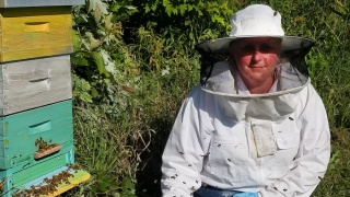 Erin Duval wearing bee suit next to her honey bee hives.
