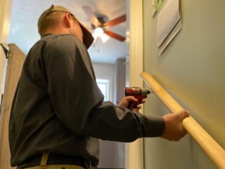 A person installs a handrail on a stair to improve safety.