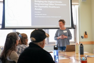 A person presents in front of a screen at the Health Equity Summit in Burlington, VT.
