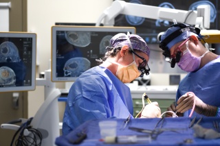 Katrina Ducis, MD, a neurosurgeon with UVM Health – UVM Medical Center, performing surgery with Dylan Adams, MD, senior neurosurgery resident.