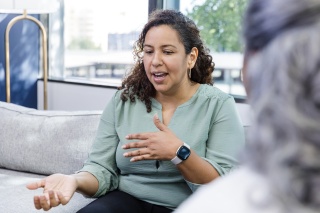 Adult woman talks with a clinician while seated on couch.