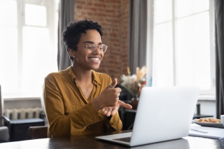 Adult woman smiles while meeting remotely on a computer.