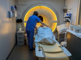 A medical provider supports a patient in getting into a MRI.