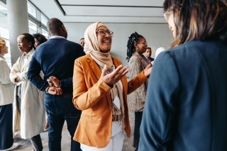 Adult wearing a head scarf or hijab speaks to a group of people.