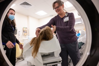 Two medical providers assist a patient getting ready for an MRI.