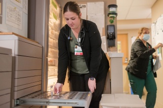 Nurse selects medication from an automated dispensing cabinet.