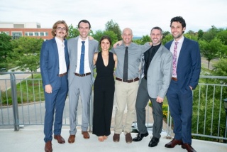 Group photo of the six Emergency Medicine 2023 alums standing outdoors on a balcony.