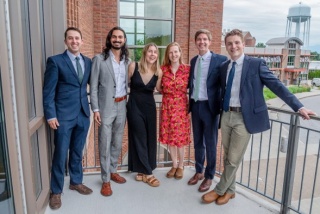 Group photo of the six Emergency Medicine 2024 alums standing outdoors on a balcony.