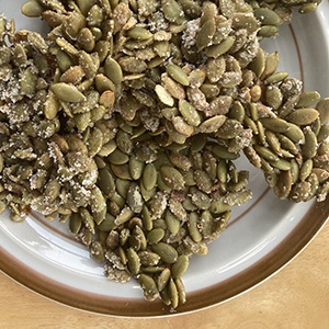 Pumpkin seed pepita brittle snack sits on a white plate.