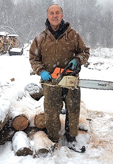 TAVR patient Doug Varney stands with a chainsaw and firewood.