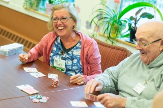 A Home Health and Hospice nurse plays poker with an adult male patient.