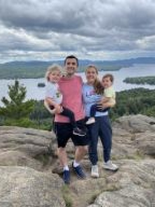 Zach Zimmer, MD with family on rock outcrop in front of lake and mountains