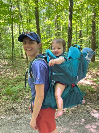 Alyssa Dicosmo hiking with a child on a backpack.