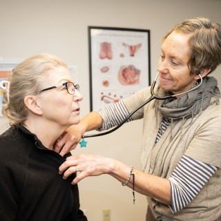 An OB GYN provider listens to a patients heart during a gynecology visit.