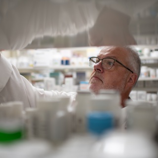 A pharmacist looks through prescription medicine bottles.