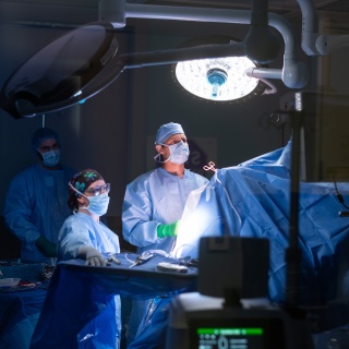 Surgeons look on to a screen during a surgery.