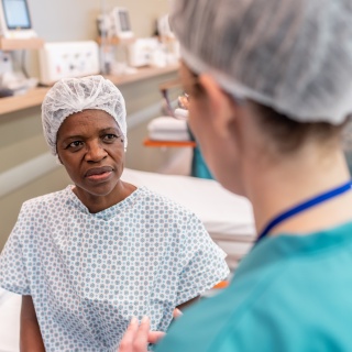 A woman speaks with a medical provider prior to surgery.