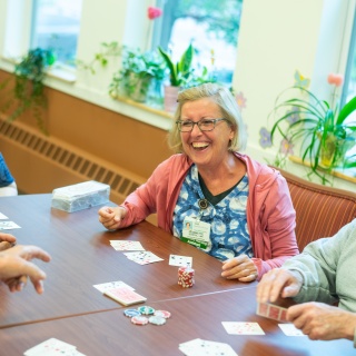 Residents sit around a table laughing and playing cards.