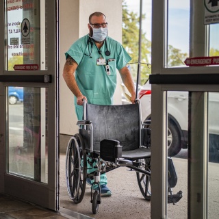 A Champlain Valley Physicians Hospital employee enters the building with a wheelchair.