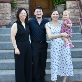 Group photo of OBGYN residents posing outdoors. One resident holds a toddler.